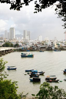 Cai Nehri ağzındaki tahta balıkçı tekneleri Nha Trang, Khanh Hoa 'daki Po Nagar cham kulesinden arka planda şehir merkezindeki gökdelenler, Cu Lao köyünde tuzlu su. Vietnam