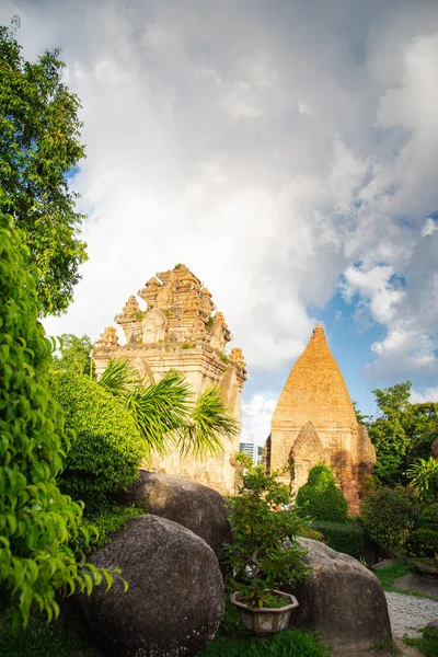 Well trimmed bush landscape with North Tower or Thap Chinh and Central Tower or Thap Nam of Ponagar Cham Towers background, terraced pyramidal roof, built partly of recycled bricks, blue sky. Vietnam