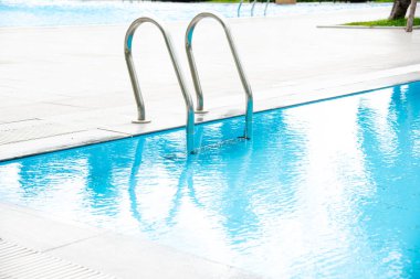 Paslanmaz çelik merdiven merdiveni, temiz su, mermer kenar ve çizgisel drenajları olan karmaşık bir yüzme havuzu. Lüks otel tatil beldesi. Boşluğu kopyala