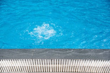Üst düzey yüzme havuzuna filtre pompasıyla su sıçrat doğrusal drenaj, mermer kenar, kılcal dalgalı temiz su, açık hava eğlencesi. Boşluğu kopyala