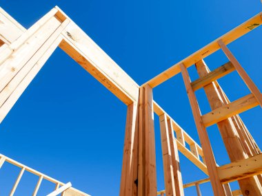 Dallas, Teksas 'ta, orta büyüklükteki tek bir aile evinin yeni temelinde kapı ve pencereler için kaba açıkları olan ahşap dış ve iç duvarlar, açık mavi gökyüzü. ABD