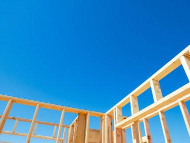 Dallas, Teksas 'ta, orta büyüklükteki tek bir aile evinin yeni temelinde kapı ve pencereler için kaba açıkları olan ahşap dış ve iç duvarlar, açık mavi gökyüzü. ABD