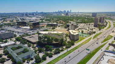 Business park group of office buildings, hotels, restaurants in Love Field neighborhood with downtown Dallas in background, sunny clear blue sky, busy traffic on Stemmons Freeway I35, aerial view. USA clipart