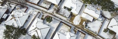 Panorama view row of single-family houses covered in heavy snow on shingles roofing, residential street suburban Dallas-Fort Worth metropolitan, severe weather, climate change, sunshine melting. USA clipart
