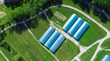 Aerial view high tunnel greenhouse on large grassy vacant land of large commercial farm in rural Ozarks aera, Mansfield, Missouri, row polyhouse, hoophouse extra-long polythene growing hothouse. USA clipart