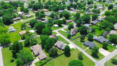 Residential neighborhood along Jefferson and Gentry Ave in Checotah, McIntosh County, Oklahoma, row of single-family houses with large backyard, grassy lawn, lush green tall mature trees, aerial. USA clipart