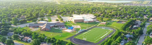 stock image Panorama view lakeside urban sprawl green neighborhood, school district sport complex football field, tennis court, running track, playground in residential area Dallas Fort Worth suburbs, aerial. USA