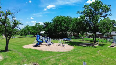 Checotah, McIntosh County, Oklahoma 'daki banliyö yerleşim bölgesinde oynayan çocukların olduğu açık mahalle çocuk parkı. Yeşillik çim parkı, orta gelirli evler, hava manzarası. ABD