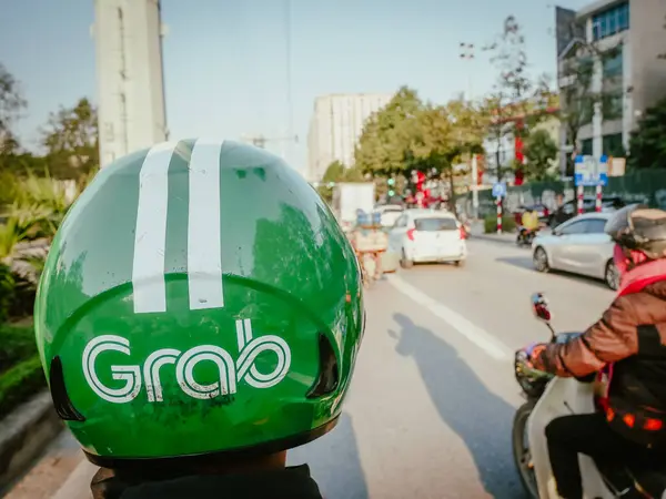 stock image DEC 22, 2023-HANOI, VN: Ha Noi street early morning with close-up view helmet of Grab ride sharing driver using motorbike, Grab is Southeast Asia leading superapp, Singapore-based technology company