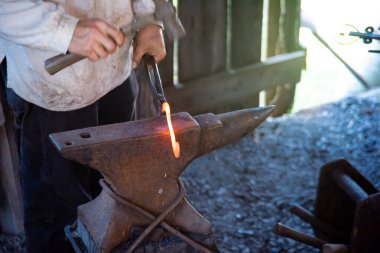 Demirci eli, Mansfield, Missouri 'deki geleneksel ticaret atölyesinde ortaçağ örslerinde eriyen demir nallar dövmek için çelik perçin ve çekiç kullanan uzun karbon çelik maşa kullanıyor. ABD