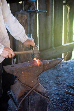 Demirci eli, Mansfield, Missouri 'deki geleneksel ticaret atölyesinde ortaçağ örslerinde eriyen demir nallar dövmek için çelik perçin ve çekiç kullanan uzun karbon çelik maşa kullanıyor. ABD