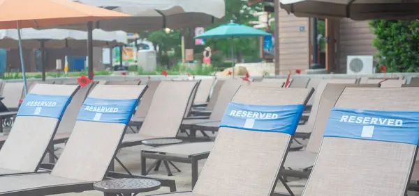 stock image Panorama row of pool lounge chairs with reserved words wrap around, small plastic service flag at upscale hotel resort swimming, Grapevine, Texas, exclusive private seating, summer holiday event. USA