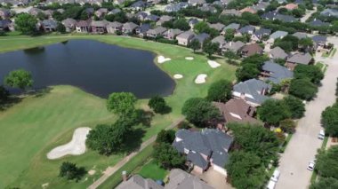 Golf sahası göleti golfçülerle dolu, kulüp arabaları lüks konutlarda taşınıyor büyük malikaneler beton döşemeler çatılar, yüzme havuzu Plano, Teksas, Dallas Fort Worth Metroplex 'in doğusunda.