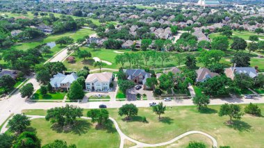 Club cars pathway in upscale golf course community with row of large mansion houses, grassy lawn, wealthy residential neighborhood in North Plano, Dallas Fort Worth Metroplex, Texas, aerial view. USA clipart