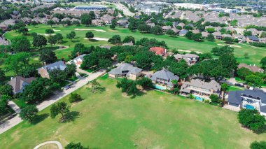 Varoş parkında geniş çimenli bir alan var. İki katlı konak, yüzme havuzu, golf sahası çevresi North Plano, Dallas Fort Worth Metroplex, hava manzaralı. ABD