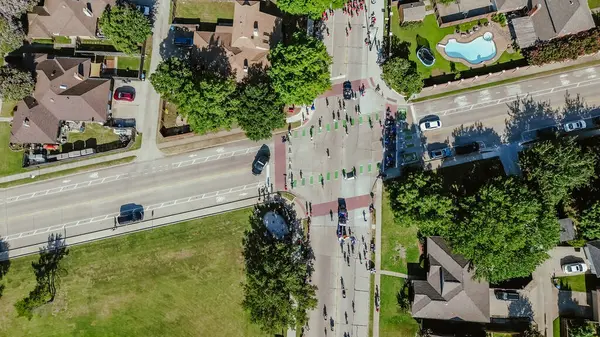 stock image Suburban street intersection with Fourth of July traditional parade event for Independence Day at Coppell, Texas, upscale residential neighborhood single family house swimming pool, aerial view. USA