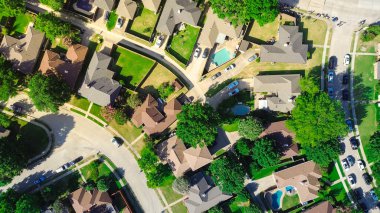 Dallas Fort Worth Metroplex 'in kuzeyindeki Coppell' de sokak geçidini izleyen insanların bulunduğu yerleşim yerlerinde park halinde uzun bir araba kuyruğu var. Zengin bölgelerde büyük banliyö evleri yüzme havuzları, antenler. ABD