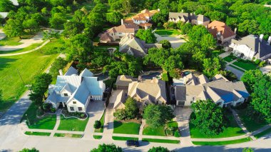 Suburban park lush green trees, concrete walking path in wealthy residential neighborhood with large mansion houses, swimming pool, concrete roof tiles, Dallas Fort Worth metroplex, aerial view. USA clipart