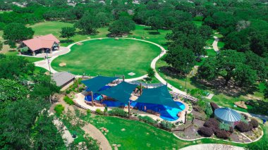 Barınağı olan bir banliyö parkı, panjurlu bir ev, geniş bir modern çocuk dinlenme merkezinde su oynayan farklı çocuklar, Texas, Flower Mound 'da yemyeşil ağaçlar, hava manzarası. ABD