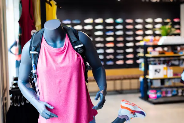 Stock image Woman mannequin wears pink running shirt, short, water vest hydration bladder hose and blurry shoes wall display at upscale sport outdoor boutique store in Southlake, Texas, endurance training. USA