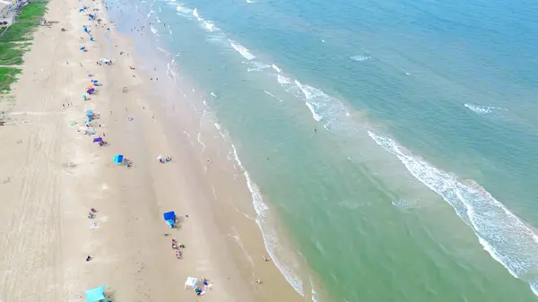 stock image Sandy shoreline, calm waves emerald water along row of beach condos, hotels, resort in South Beach, South Padre Island, exquisite barrier Gulf Coast of Texas, people enjoy beach activities aerial. USA