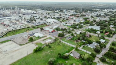 Small agriculture agro-town along highway with large oil refinery complex plant, gas flare, crude oil distillation unit, storage tanks, utility systems, pipelines, San Antonio, Texas, aerial view. USA clipart