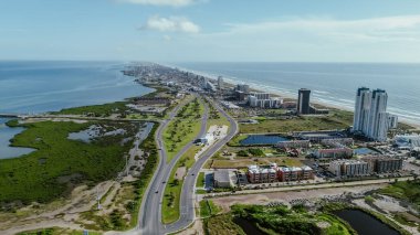 Downtown South Padre Island along Padre Boulevard, State Park Road 100 from Isla Blanca Beach, high-rise condos, beach-front hotels, white sandy beaches turquoise water, calm waves, aerial view. USA clipart