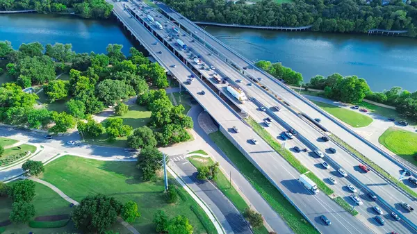 stock image Highway 35 across Colorado River in downtown Austin, riverside boardwalk cut thru lush greenery trees bank shore in South side of city urban core to Travis Heights community neighborhood, aerial. USA