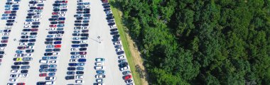 Panorama lush greenery trees near busy dense parking lots full of electric and gas vehicles, parallel pattern pavement marking number, parking management in metropolitan urban area, aerial, Texas. USA clipart