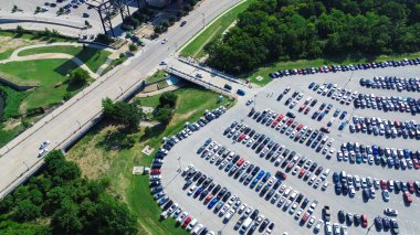 Parking lot near main boulevard street, lush greenery trees, full of electric and gas cars parked on parallel pattern with pavement marking, parking management in metropolitan urban area, aerial. USA clipart