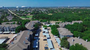 Multistory apartment buildings with covered parking near lush greenery suburban park along Baird Farm Road in North Arlington, Texas, water tower, city stadium in background, master planned area. USA clipart