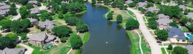 Panorama aerial view urban sprawl HOA community with neighborhood pond, mature trees cover row of upscale two-story houses, swimming pool, in Keller, Tarrant County, Texas, suburbs Dallas, aerial. USA clipart