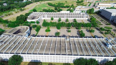 Rooftop multilevel garage with angled parking lot design, shade structure at suburban office campus building in Westlake, suburb Dallas Fort Worth, North Texas, lush green surrounding, aerial. USA clipart