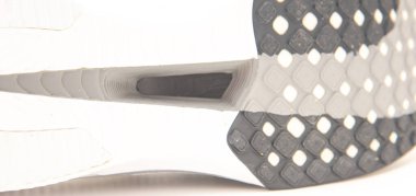 Panorama görünümlü karbon kaplamalı koşu ayakkabıları beyaz arka planda izole edilmiş karbon fiber plakaya yerleştirilmiş, plaka yorgunluğu azaltıyor, her adımda enerji geri dönüşünü artırıyor. ABD