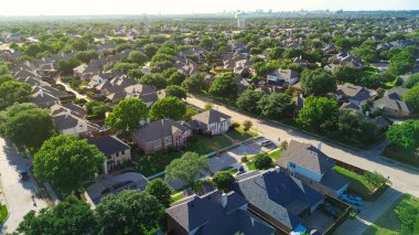 Two story suburban houses in West Plano, Texas with city water tower, downtown buildings skylines background, upscale neighborhood tree lined street in Wentworth Estates, suburbs Dallas, aerial. USA clipart