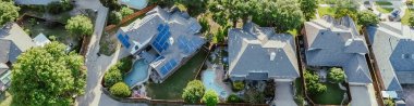 Panorama aerial view solar roof panel on corner house of upscale residential area in West Plano, Texas, two story suburban home lush green trees, clean energy, suburbs Dallas Fort Worth metroplex. USA clipart