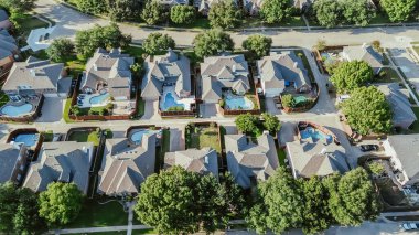 Row of upscale single-family homes with inground swimming pools, large two-story suburban mansion houses in West Plano, suburbs Dallas Fort Worth metroplex, lush green tree lined street, aerial. USA clipart