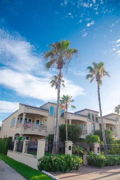 stock image Proudly display of American flag on second story porch of upscale beach houses, metal fence font yard, clay tile roofs, sunny cloud blue sky in South Padres Island, travel destinations Texas. USA