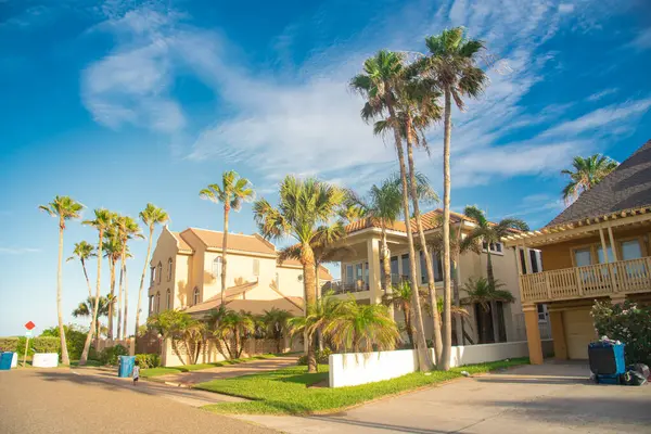 stock image Row of two-story beach house vacation home rental property with porch, clay tile roofs with line of palm trees under sunny cloud blue sky near downtown South Padres Island, travel destinations. USA