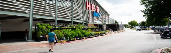 stock image SCHERTZ, TX, US-JUL 25, 2024: Panorama view customer enter H.E.B Plus grocery store from busy parking lots sunny sky, San Antonio based private supermarket chain more than 380 stores in US and Mexico