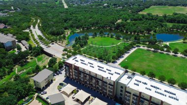 Endüstriyel çatı ambalajlı klima, modern apartmanın çelik dolabında bulunan kazan daireleri yemyeşil şehir parkının yanında gölet, patika, Keller Texas 'ın çimenli meydanı, anten. ABD