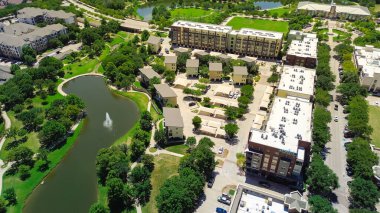 Rooftop packaged AC, furnace units at multistory modern urban apartment complex with covered carport near Keller Texas town center square walking jogging trails, retail shops, restaurants, aerial. USA clipart