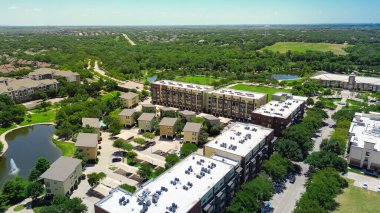 Parkın kenar mahalleli apartman kompleksi çatı döşemesi endüstriyel çatı ambalajı ağır çelik dolapta fırın birimleri yemli yeşil park göleti, Keller Texas yolları. ABD