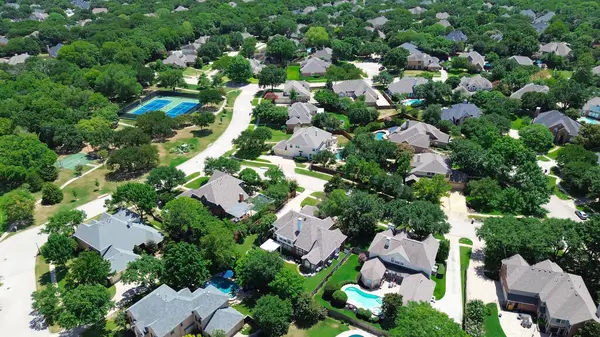 stock image Tennis and basketball courts in upscale residential neighborhood surrounding lush green trees, row of two-story houses swimming pools in Keller, suburbs Dallas Fort Worth metroplex, Texas, aerial. USA