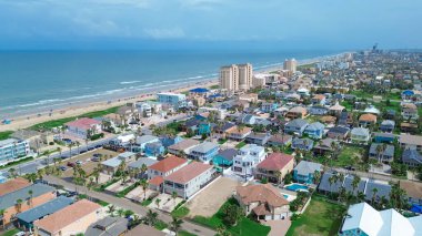 Sahil şeridi sakin dalgalar Güney Padre Adası, Teksas, rengarenk plaj evleri yüzme havuzları, rıhtım evleri, tatil yerleri, kiralık tatiller, insanlar yüzme, antenler. ABD