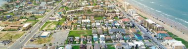 Panorama aerial sandy shoreline calm waves tropical South Padre Island, Texas, colorful painted beach houses swimming pools, waterfront condos, resort, hotels, vacation rentals, people swimming. USA clipart