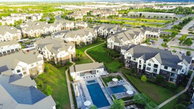 Modern swimming pool and spa in new development apartment complex with metal roofing, siding in fast growing area near Pflugerville northeast of downtown Austin, Texas, housing market, aerial. USA clipart