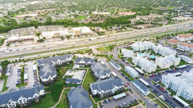Austin, Teksas 'ın kuzeydoğusunda otoyol I-35 yoğun trafiği. Boyalı yeni apartman kompleksi çatıları, kalabalık açık hava parkı, kiralık ev, konut pazarı, anten. ABD