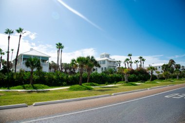 South Padre Adası yakınlarındaki okyanus bulvarı, State Park Road 100 boyunca uzanan yol kenarındaki plaj evleri, çok katlı beyaz renkli kiralık evler güneşli mavi gökyüzü. ABD