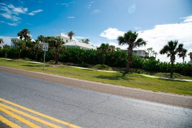 Speed limit 45mph in upscale residential neighborhood beach houses along State Park Road 100, Ocean boulevard near downtown South Padre Island, multistory white painted mansion homes, palm trees. USA clipart